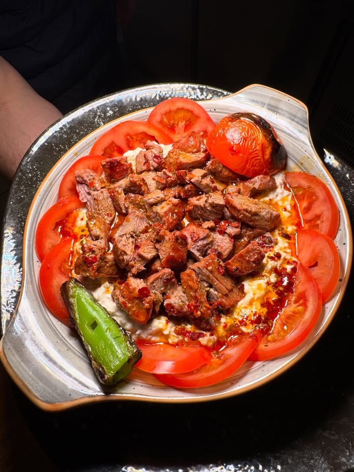 Sizzling meat dish with tomatoes and peppers at LARA KITCHEN
